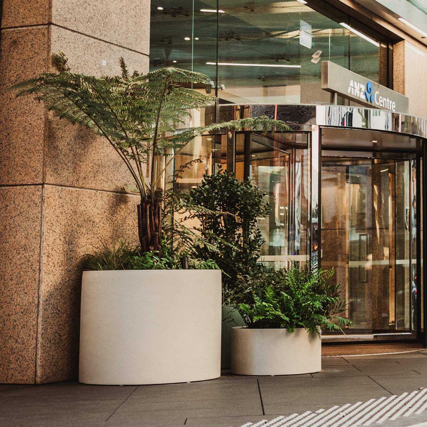Modern building entrance with glass doors and potted plants.